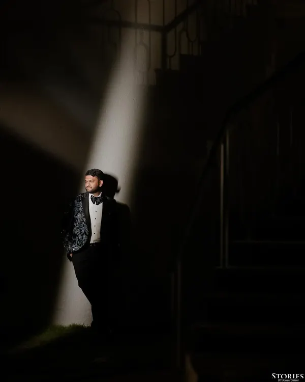 A dramatic portrait of the groom, Shivam, using a single spotlight to create a cinematic, high-contrast look before his cocktail party.