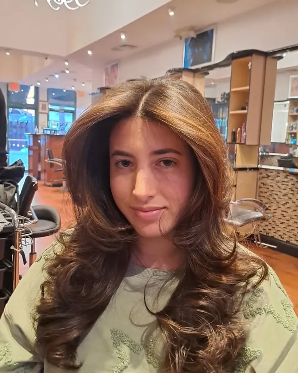 A classic layered haircut finished with a bouncy, voluminous blowout. This style adds body and movement to long hair.