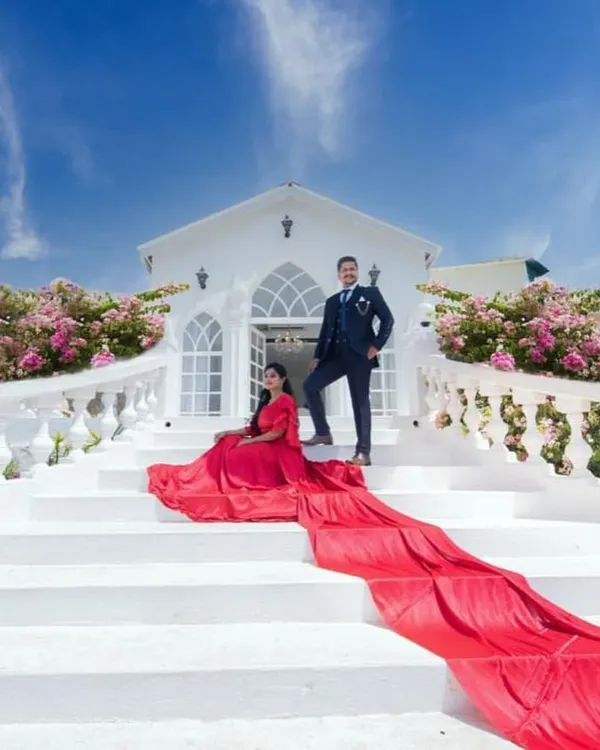 This is the fairytale moment you've been dreaming of. Our dramatic red trail gown creates a breathtaking contrast against any backdrop, making your pre-wedding photos unforgettable. Paired with a classic navy suit for him, this is a coordinated couple look that spells pure romance.
