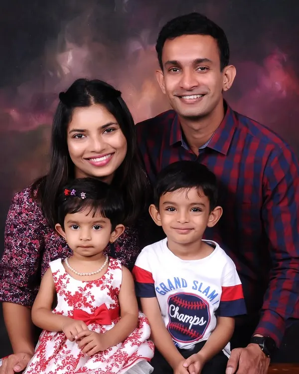 A classic studio family portrait against a warm, painted backdrop. I focus on capturing a relaxed and happy moment with both parents and children looking their best.