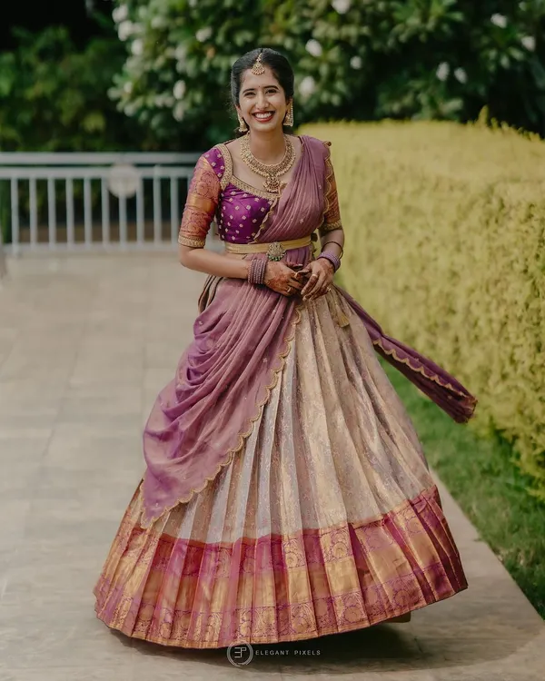 A full view of a traditional half-saree (Langa Voni) I designed for a client. The off-white Kanchivaram skirt is paired with a vibrant purple brocade blouse and a draped dupatta.