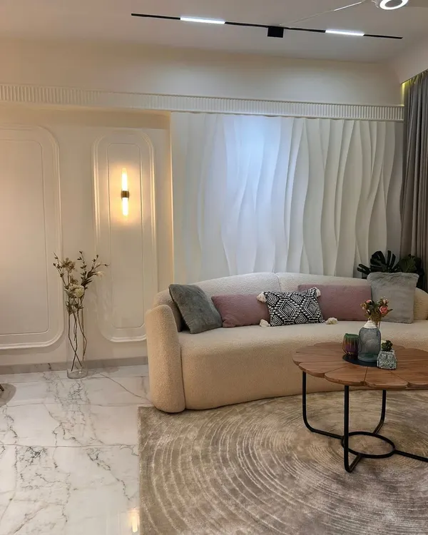 A closer look at this serene living area, where a curved sofa adds a soft, modern touch. The 3D wall paneling creates subtle texture and depth, while the marble flooring provides a timeless, luxurious foundation.