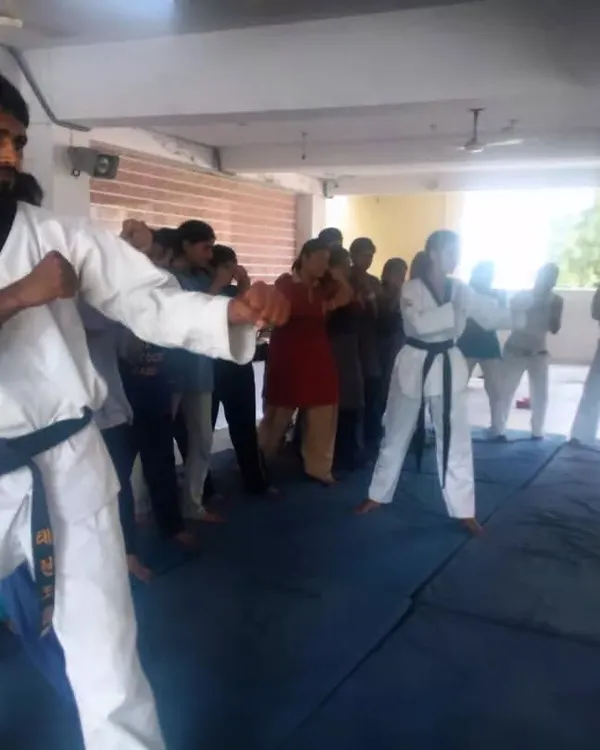 An instructor leads a self-defense workshop for women, demonstrating a blocking technique. Our workshops focus on practical, easy-to-learn moves for real-world situations.