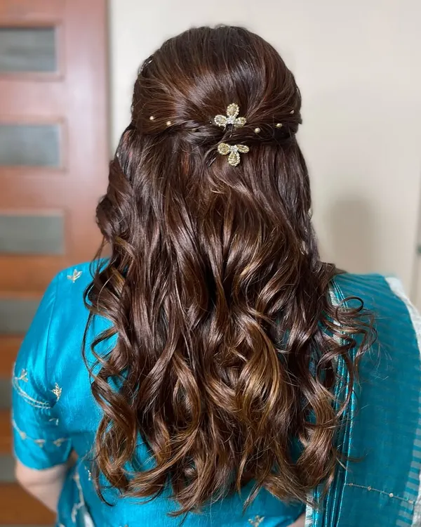 A close-up of the elegant half-up hairstyle for the mom-to-be. The soft curls are gathered with a twist and adorned with delicate, sparkling butterfly clips.