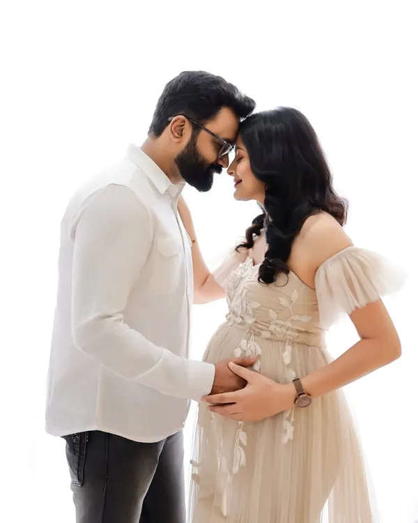 An intimate black and white portrait capturing the quiet connection between expecting parents. Their gentle embrace and shared smiles tell a story of love and anticipation.