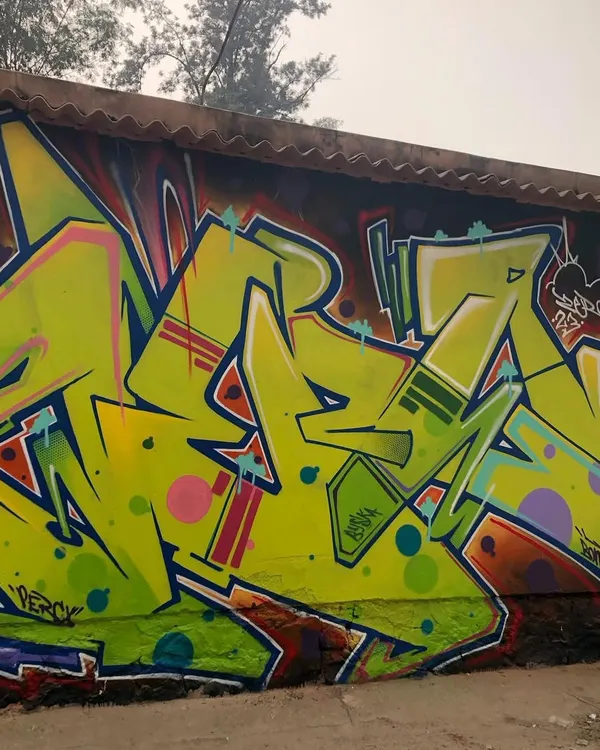 A classic wildstyle piece, showing complex, interlocking letters in a vibrant lime green. This is a more traditional graffiti style, focused on letter structure and flow.