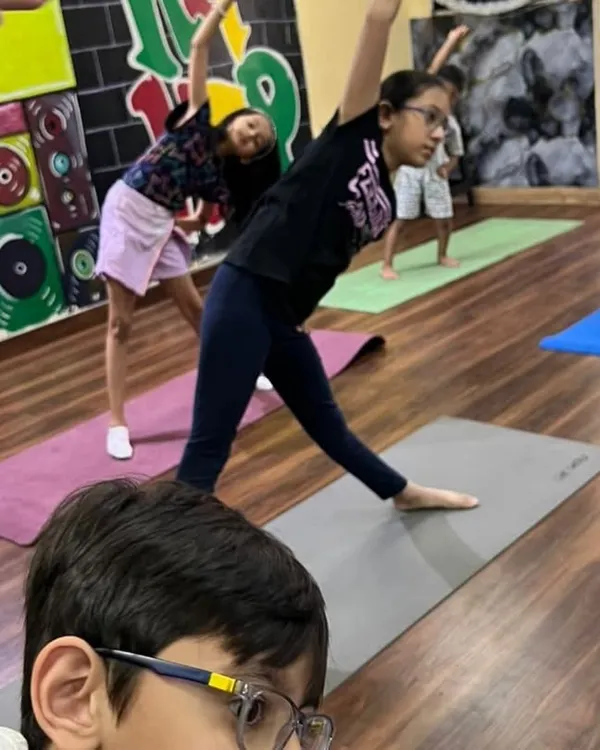 The triangle pose, or Trikonasana, is great for stretching and balance. Here, the kids are learning the pose together during a summer yoga session.