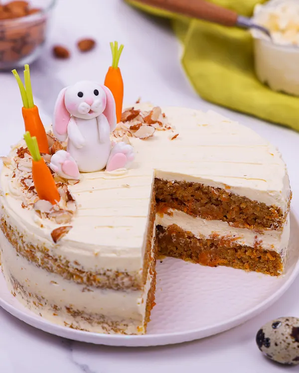 Our Easter Carrot Cake is a classic, beautifully decorated with a fondant bunny, edible carrots, and toasted almonds.