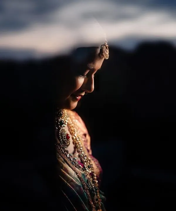 A beautiful bridal portrait using reflection and dramatic lighting. This artistic approach creates a soft, ethereal image that highlights the bride's profile.