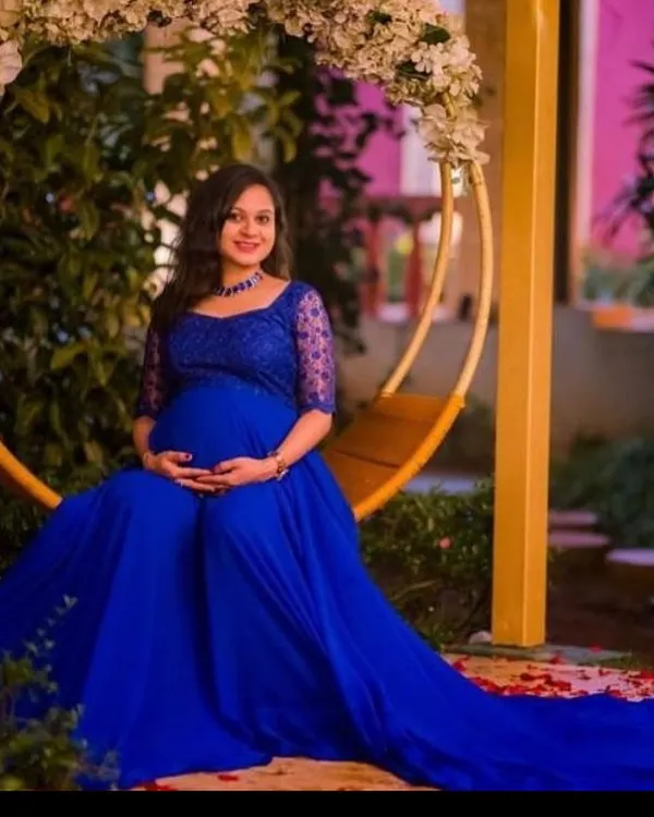 A serene moment on a floral swing. This royal blue maternity gown features delicate lace sleeves and a flowing skirt, perfect for capturing the peaceful joy of expecting.