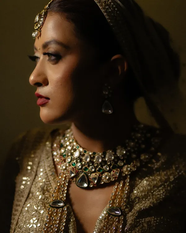 A dramatic close-up of the bride, where shadows and light play across her face, highlighting her stunning jewelry and bold makeup. A truly artistic bridal portrait.