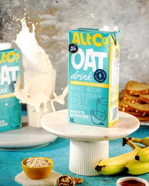 A high-energy splash shot for Alt Co.'s oat milk. The dynamic splash creates a sense of refreshment and excitement, while the surrounding bananas and oats highlight the natural ingredients.