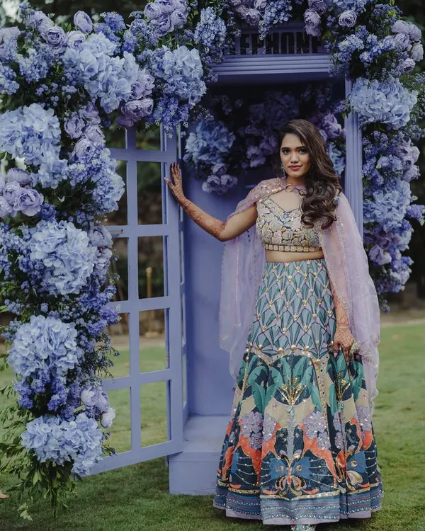 A portrait of the bride by a stunning photo booth I designed. The door is framed with an abundance of purple hydrangeas, creating a whimsical and romantic backdrop for photos.