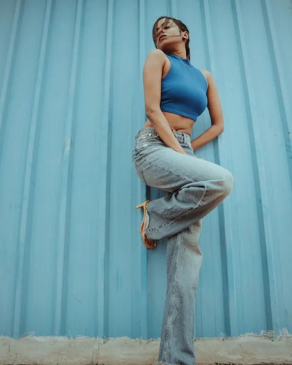 This pose adds a dynamic angle to a simple setup. The monochromatic blue palette creates a visually striking image for a modern fashion catalogue.