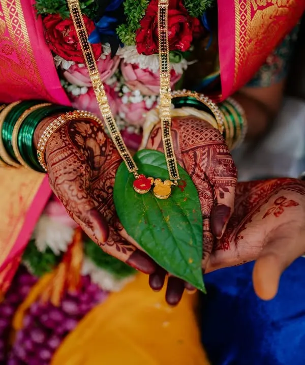 A beautiful detail shot of the Mangalsutra, a sacred symbol of marriage in Maharashtrian culture, held in the couple's hands. Capturing these details is key to telling the full wedding story.