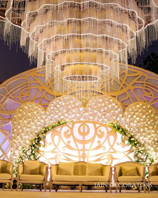 I designed this reception stage for pure opulence. A massive, cascading crystal chandelier hangs above a backdrop of white roses and intricate latticework, creating a setting of unparalleled luxury for the newlyweds.