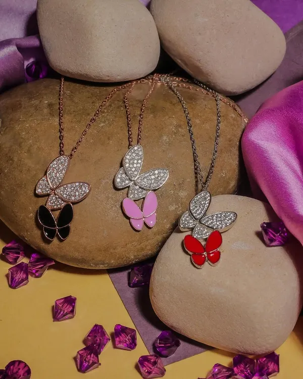 A product photoshoot featuring butterfly-themed necklaces in various colors. I used natural stones and a textured background to create an earthy, appealing aesthetic for this e-commerce jewelry collection.