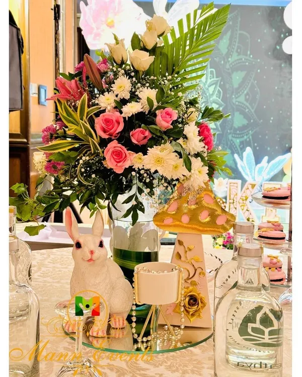 The devil is in the details. For this whimsical party, the table centerpieces included fresh floral arrangements, a cute rabbit figurine, and a themed mushroom prop, all coming together to create a magical tablescape.