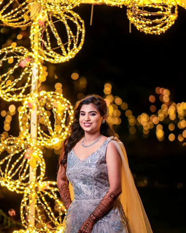 A radiant bridal portrait taken at night, with the warm glow of decorative lights creating a beautiful bokeh background.