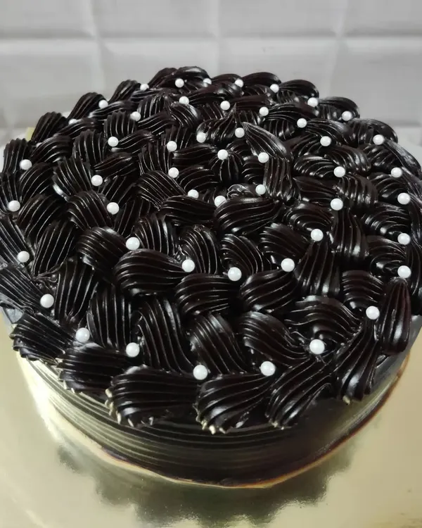 I love the challenge of creating detailed frosting designs. This rich chocolate cake features an intricate basket-weave piping technique, with each swirl carefully placed and dotted with delicate white pearls for an elegant finish.