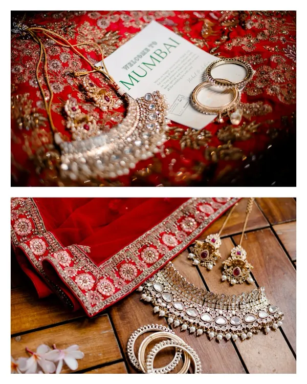 A flat lay of the bride's stunning jewelry, her red lehenga, and a 'Welcome to Mumbai' card. We love styling and capturing these detail shots that set the scene for your wedding story.