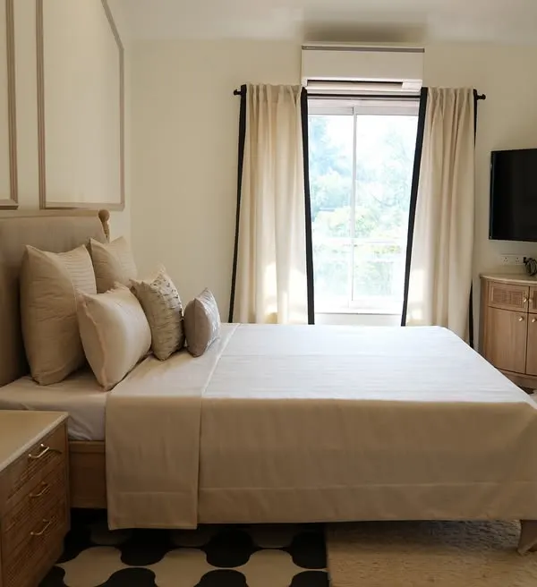 A master bedroom we designed for a villa in Alibaug, created to be a sanctuary of calm. The space features our neutral layered bedding, a custom upholstered headboard, and elegant curtains with a contrasting border.