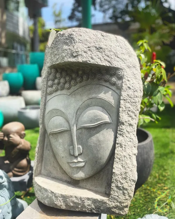This serene Buddha face mural, carved into a solid block of stone, is a powerful symbol of enlightenment. The closed eyes and gentle smile represent a peaceful state of mind, perfect for a meditation garden or tranquil room.