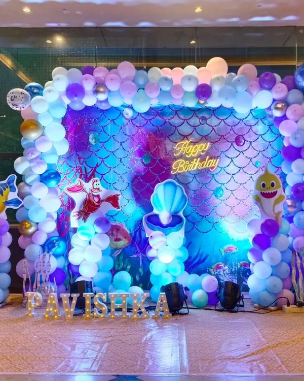 This is the hero item. I created this elaborate underwater Mermaid theme for a first birthday party. The setup includes a custom backdrop with a shimmer effect, multi-layered balloon columns, and character cutouts of Ariel and Flounder to bring the entire scene to life.
