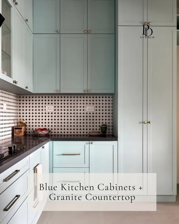This light blue kitchen showcases a beautiful material pairing of shaker-style cabinets with a classic granite countertop. The black and white patterned backsplash adds a graphic element, creating a timeless yet modern look.