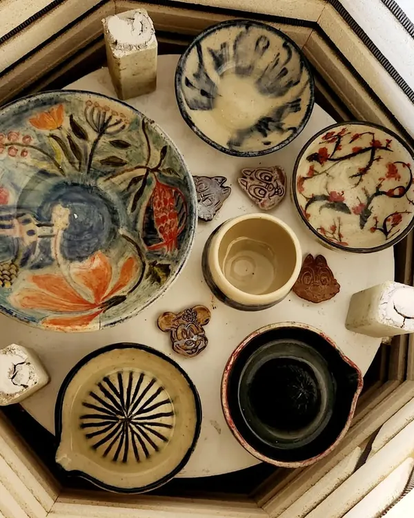 An overhead view inside my kiln reveals a collection of freshly fired custom pieces. Notice the variety, from a hand-painted floral plate and a functional citrus juicer to small bowls with unique glaze patterns.