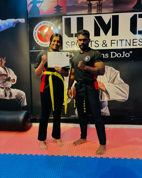A student proudly holding her certificate after successfully passing the Kickboxing Belt Grading Exam and earning her Yellow Belt.