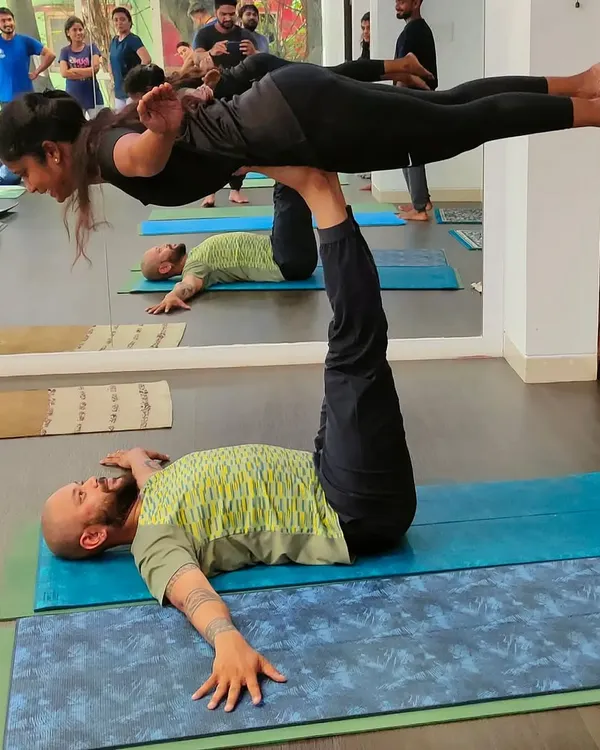 An instructor bases a student in a therapeutic Acro Yoga pose. This "bird" pose helps to lengthen the flyer's spine and is built on a foundation of trust and stability.