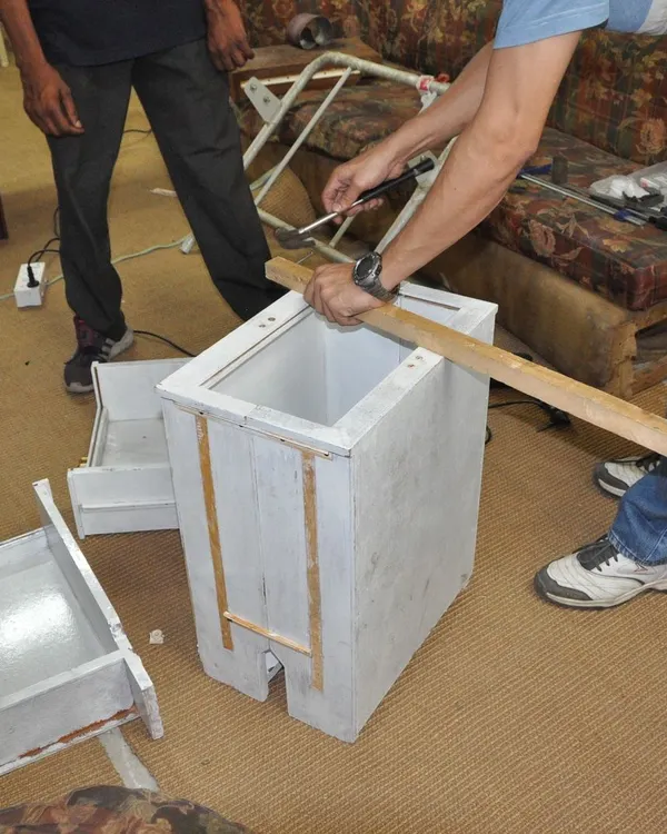 A participant works on repairing a small wooden cabinet. Our workshops provide the space and tools for you to tackle small furniture and woodwork projects.