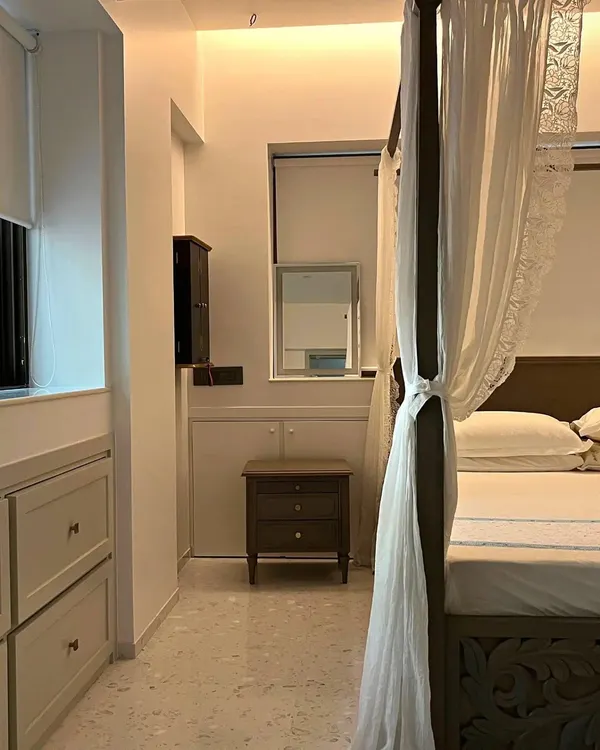A glimpse into a serene bedroom from our Bandra bohemian project, featuring a classic four-poster bed with delicate drapery that creates a soft, romantic atmosphere. The terrazzo flooring adds a touch of modern texture.