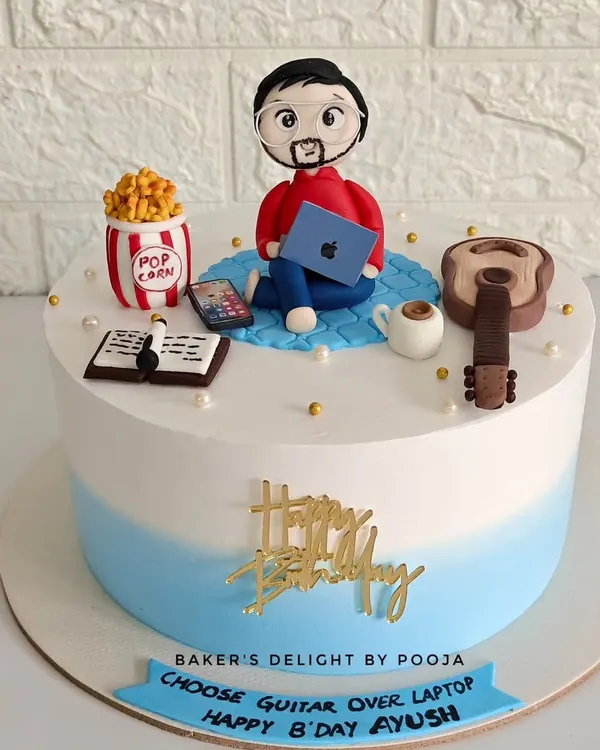 This fully customized cake was designed for Ayush's birthday, featuring a fondant figurine of him with all his favorite things: his laptop, guitar, phone, and popcorn. The banner playfully suggests he "Choose Guitar Over Laptop."