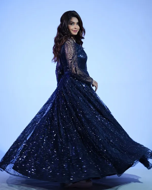 A full-length shot of the midnight blue sequin gown. The way it flows and sparkles is perfect for making a dramatic entrance at any formal event.