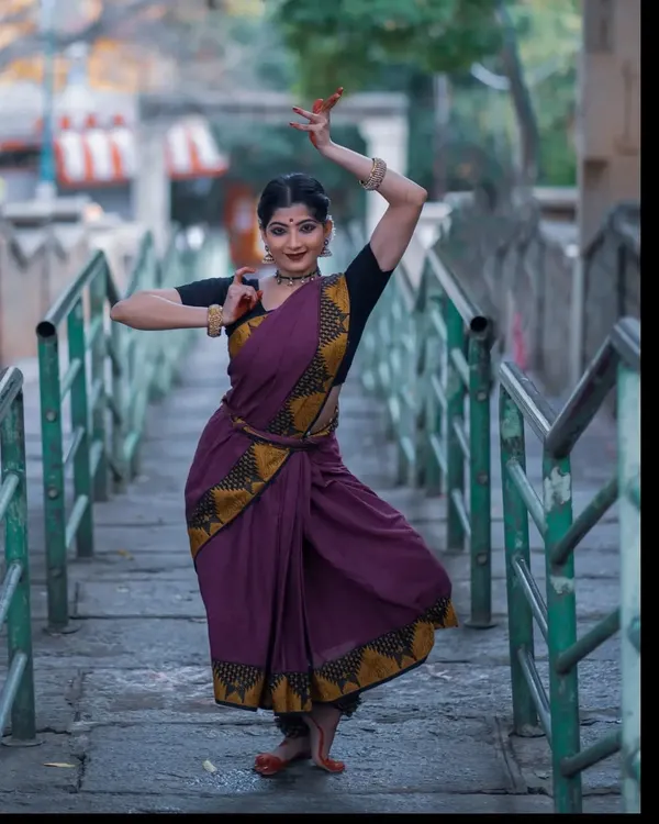 A graceful pose captured during a photoshoot at a temple. The setting provides a serene and powerful backdrop that complements the traditional aesthetics of Bharatanatyam.