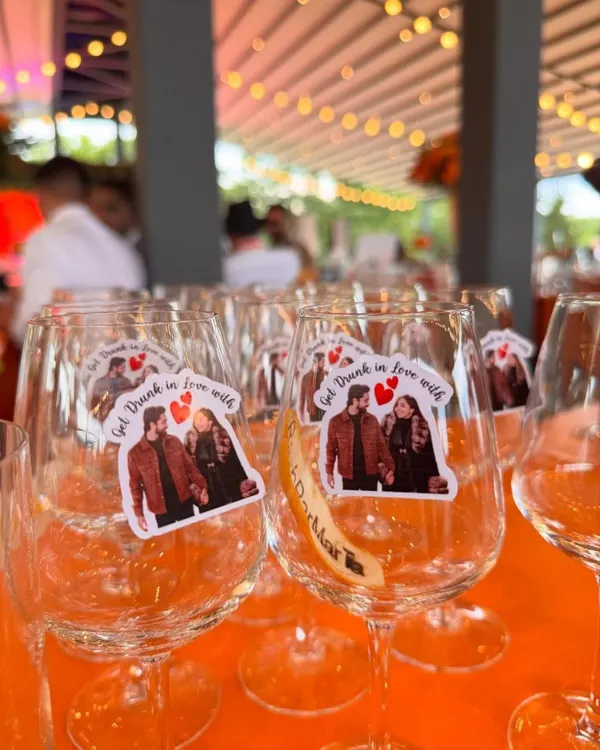 Personalization makes an event truly yours. For this Hermès-themed sundowner, we adorned the wine glasses with custom stickers featuring the couple's photo and the fun phrase 'Get Drunk in Love with', adding a charming and personal touch.