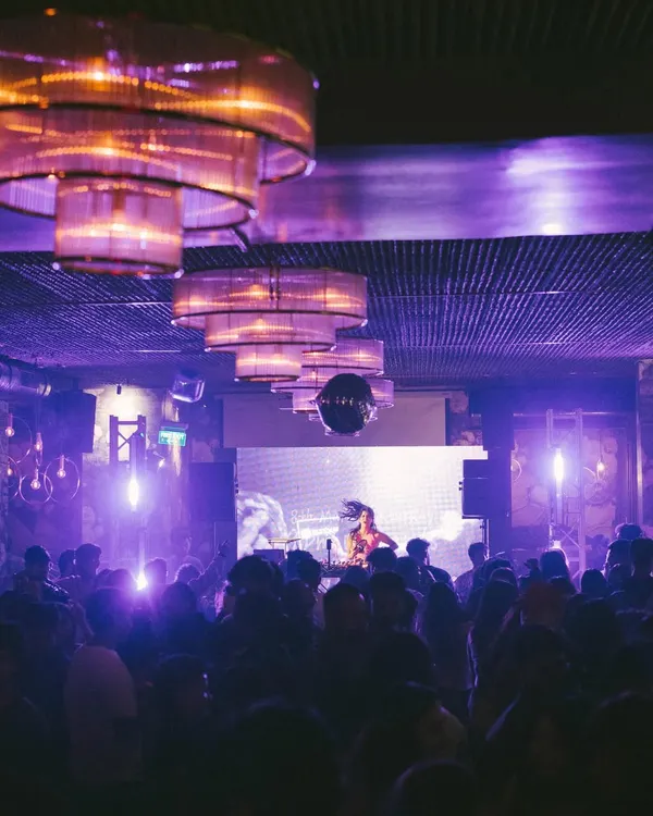 A view from my console during a packed club night. The combination of purple lights, a disco ball, and a full house is my ideal work environment.