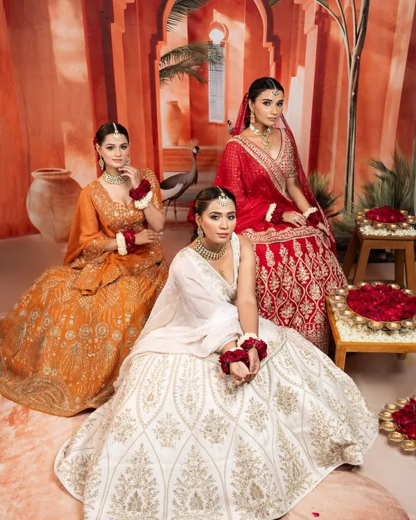 I believe in offering a spectrum of choices for the modern bride and her party. This trio of lehengas in festive red, serene white, and vibrant orange showcases the variety of moods and styles we can explore for your wedding celebrations, from the main event to the sangeet.