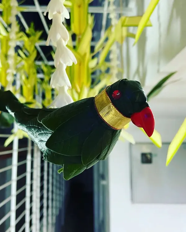 This close-up shows a handcrafted parrot made from green leaves, a traditional decorative element in South Indian events. The fine details, like the red beak and gold collar, showcase my commitment to craftsmanship.