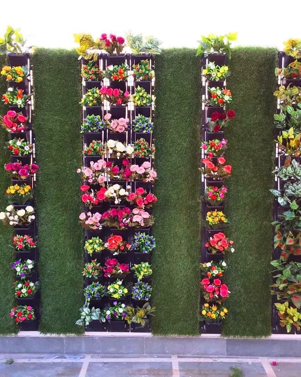 This artificial vertical garden brings a burst of color to a client's terrace. The design uses panels of colorful artificial flowers and green foliage against a turf background for a cheerful and maintenance-free look.