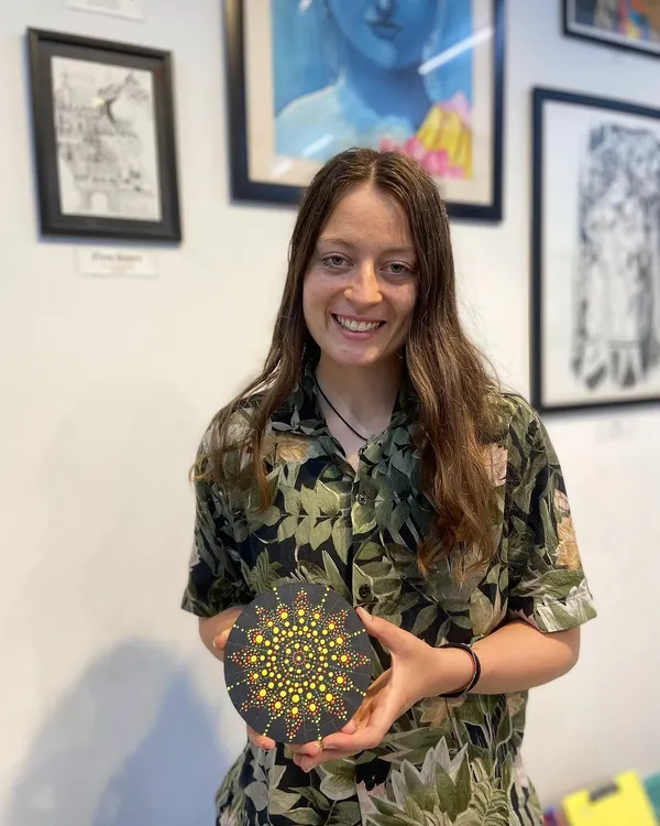 A participant proudly displays her beautiful dot mandala artwork. This therapeutic art form involves creating intricate patterns with dots, resulting in a stunning, meditative piece.