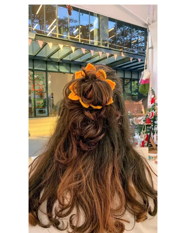 Our handmade sunflower scrunchie is a bestseller for a reason. It’s a fun and bright way to tie up your hair, shown here styled in a simple bun.