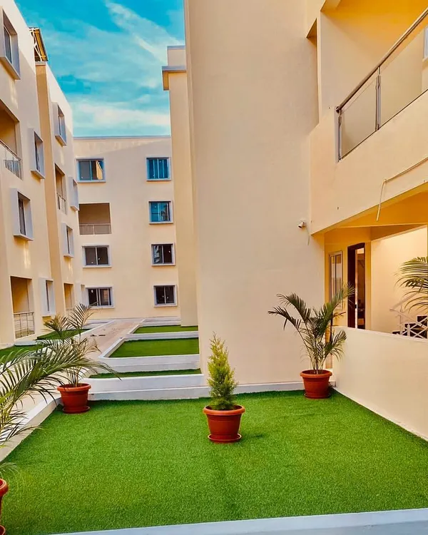 An apartment complex courtyard featuring a combination of soft artificial turf and potted faux palms. This creates a functional and attractive common area that stays green and tidy in any weather.