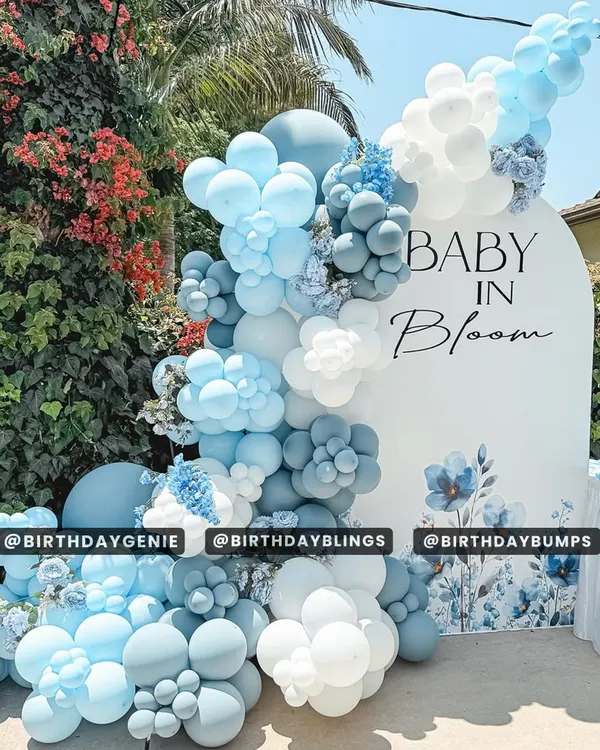 A beautiful outdoor "Baby in Bloom" baby shower, featuring a stunning balloon cascade in shades of blue and white with floral accents.