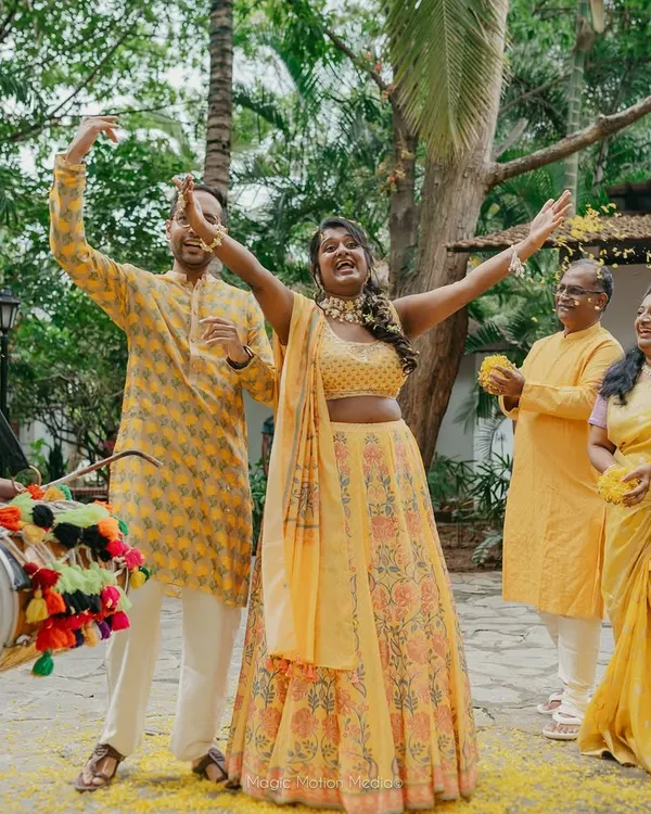 A bride's joyful entrance during her Haldi ceremony, surrounded by family and the beat of the dhol.