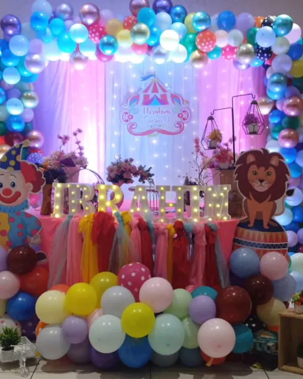 Step right up to a carnival-themed birthday party. This vibrant setup for Irfan features a colorful balloon arch, fun character cutouts like a clown and lion, and illuminated marquee letters for the name.