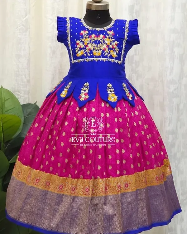 A royal combination of blue and pink. This Pattu Pavadai features a blouse with beautiful floral maggam work and a peplum waist with petal details.