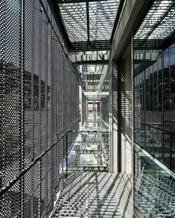 We believe modern additions should sit lightly upon historic structures. For this adaptive reuse project in Bangalore, we wrapped the original 1980s building in a delicate skin of perforated, folded metal sheets. This new filigree facade filters light and offers a new identity while respecting the old bones of the building.